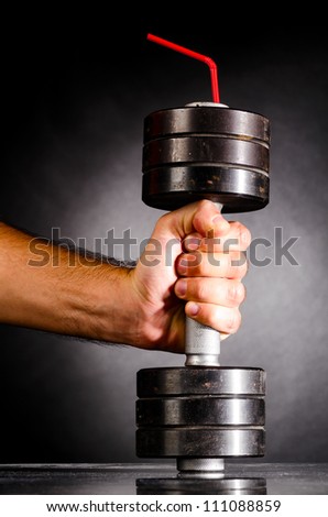 sports nutrition. male hand is holding metal barbell with red straw