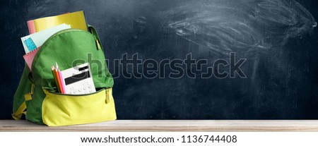 Back to school shopping backpack. Accessories in student bag against chalkboard