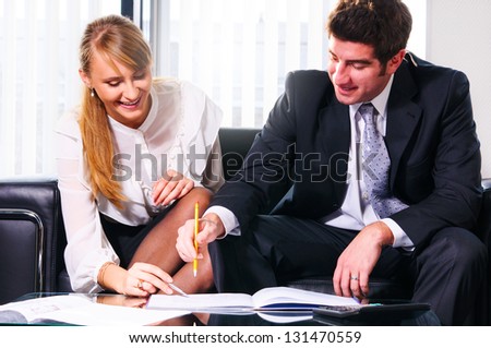 two business persons are sitting and discussing on leather sofa at office