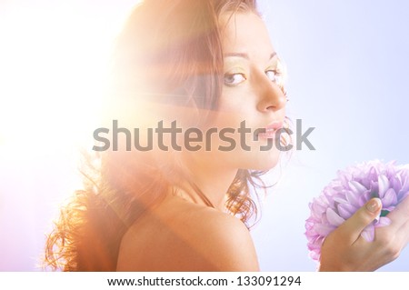 beautiful woman with big flower in sun rays