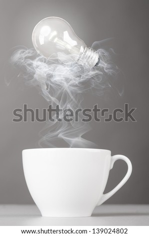 idea. bulb is lying on steaming hot coffee cup