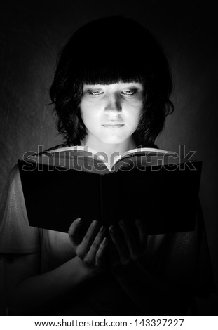 young beautiful woman is illuminated by a glowing book
