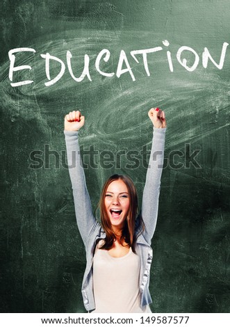 excited student woman is standing with chalk board behind her