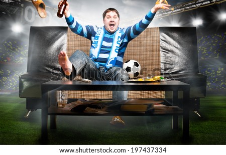 happy soccer or football fan on sofa at stadium