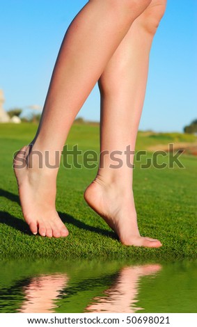 beautiful female legs on grass near lake