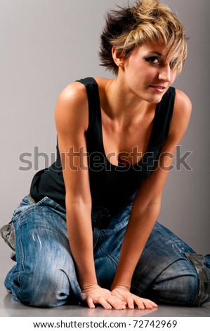 sexy fashionable knelt down woman wearing black tank top and jeans