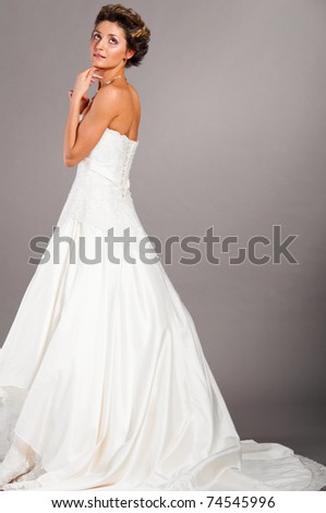  bride is standing in wedding dress on grey background side view