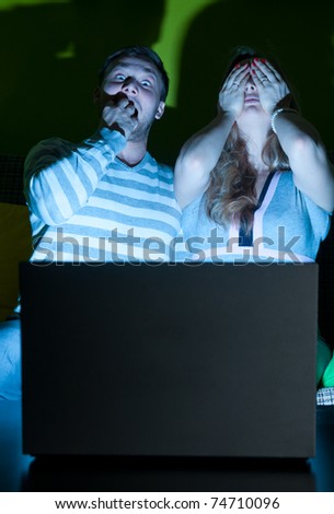 couple is watching scary movie indoors at night