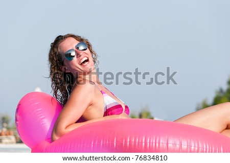 young woman is swimming in a pool on pink air bed
