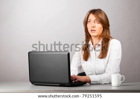 business woman is sitting in the office with laptop and thoughtfully looking at screen