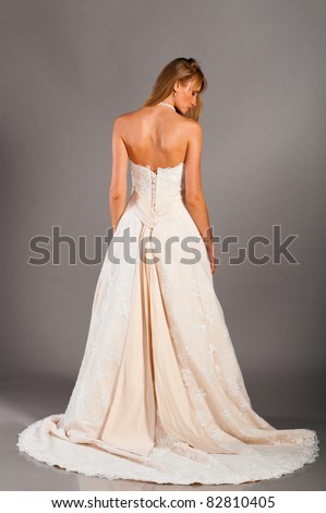  bride is standing in wedding dress on grey background view from