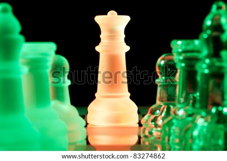 red queen and rows of green glass chess pieces is standing on board in dark