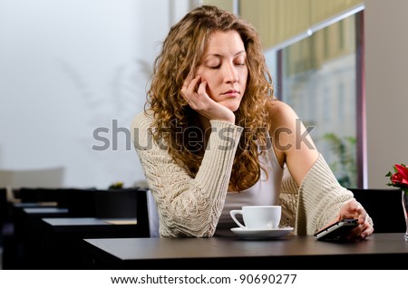 young woman is sitting at cafe and waiting for someone
