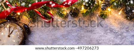Christmas fir tree with lights and clock on snow in dark, view from above