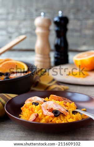 Tradition Spanish dish - valencian seafood Paella in ceramic dish with black and white Pepper and Salt Mill in the background.
