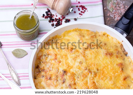 casserole with mushrooms and cabbage in frying pan with pesto, pepper and pepper mill on linen tablecloth