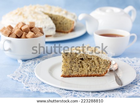 Delicious poppy seed Viennese cake with cup of tea, white tea pot and brown cane sugar on table close-up