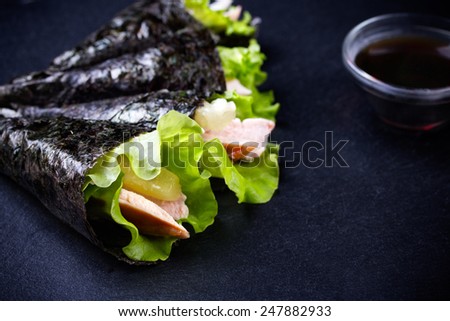 Hand-rolled temaki sushi. Traditional japanese cuisine on black slate plate