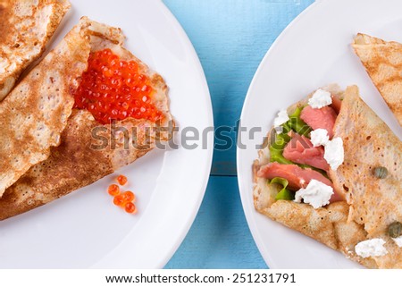 Pancake day, mardi gras, maslenitsa background. Thin rolled pancakes, crepes with red caviar and salmon. Traditional Russian dish.