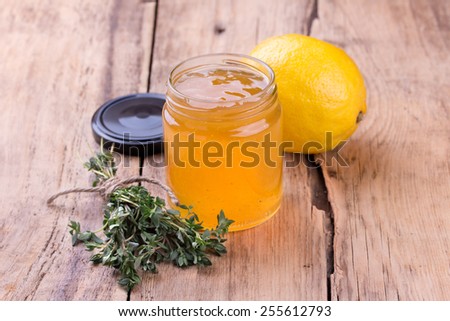 Colorful citrus jam in glass jar, thyme and lemon  on rustic wooden board