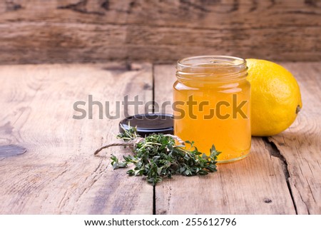 Colorful citrus jam in glass jar, thyme and lemon  on rustic wooden board. Copy space