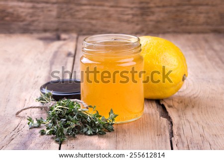 Colorful citrus jam in glass jar, thyme and lemon  on rustic wooden board