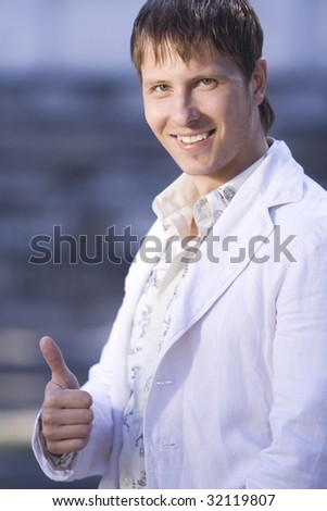smiling young man with thumbs up outside