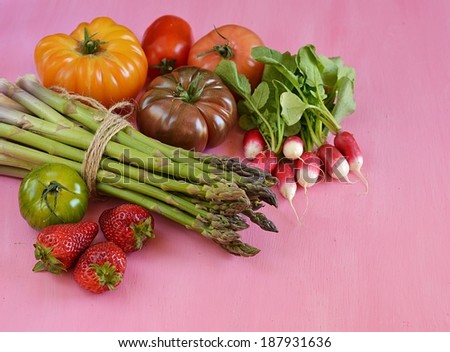 Vegetables on pink background - asparagus, tomato, radish, strawberry, mandarin