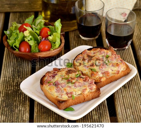 Warm open faced sandwiches with ham, cheese and sour cream served with green salad and red wine. Selective focus