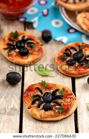 Mini pizzas with olives in shape of spider and tomato sauce. Selective focus. Shallow depth of field