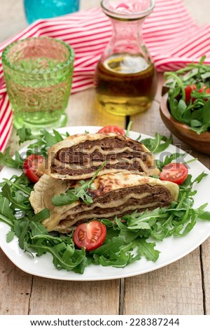 Layered meat pies with green salad and tomatoes. Selective focus on the pies