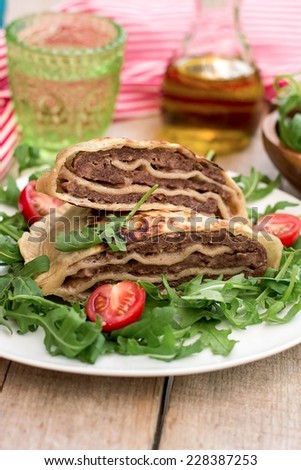 Layered meat pies with green salad and tomatoes. Selective focus on the pies