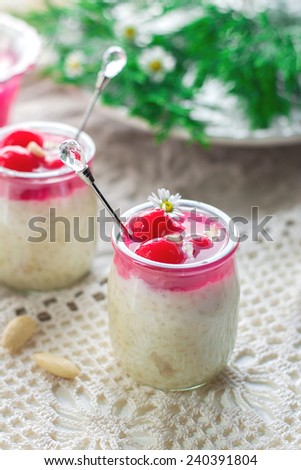Rice pudding Risalamande with almonds, whipped cream and cherry sauce. Selective focus on the cherries on top