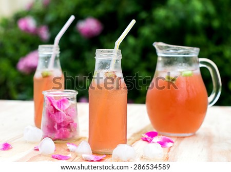 Rhubarb hibiscus drink iced tea with rose petals in the garden. Selective focus