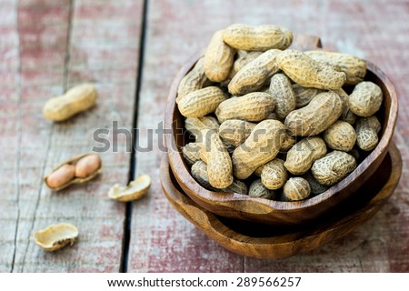 Peanuts in shell pod in bowl on wooden background. Selective focus