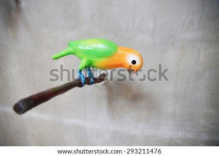 Portrait profile image of a left-facing red, green and blue macaw perched on a narrow branch against a background.