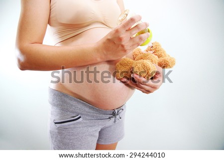 Mom in pregnancy feeding Milk a teddy bear. isolated on white