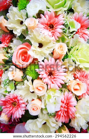 A bouquet of mixed pink flowers including roses and chrysanthemums with white gypsophila.