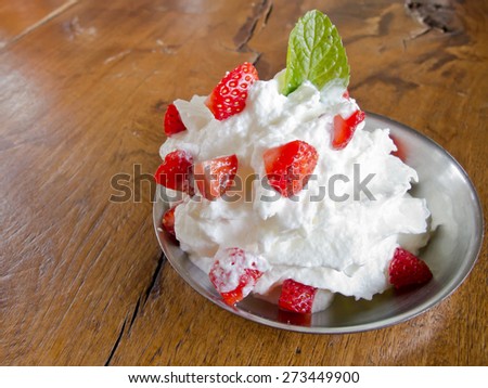 fresh cream puff with whipped cream mint and strawberries on aluminium plate and brown wood table