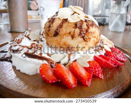 fresh cream puff with whipped cream and strawberries on white plate and brown wood table