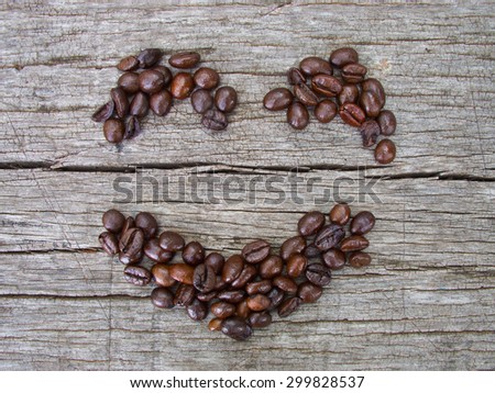 Smile face made from coffee beans on old wooden background