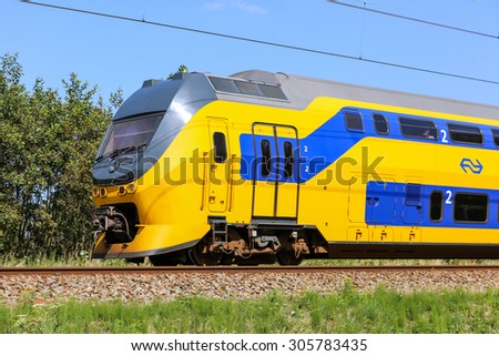 LISSE, NETHERLANDS - AUGUST 9, 2015: Dutch yellow and blue train in a green landscape