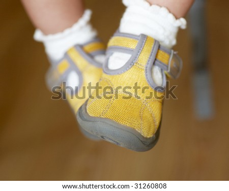 Baby\'s foot in a pair of yellow shoes.