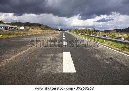 a road goes into distance with a coming storm