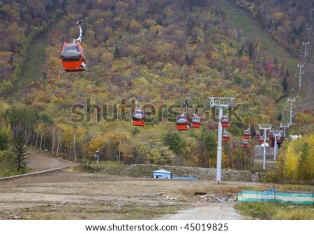 red overhead cable car over mountains in autumn