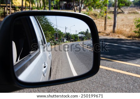 rear car mirror and rural road view