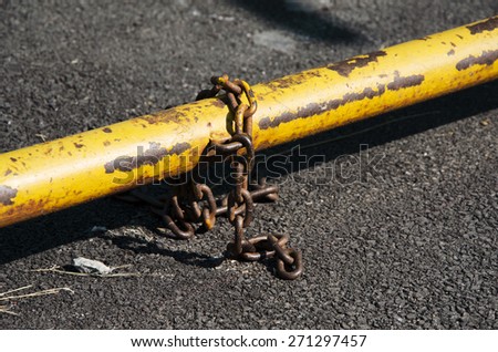 rusty anchor chain with security yellow bar