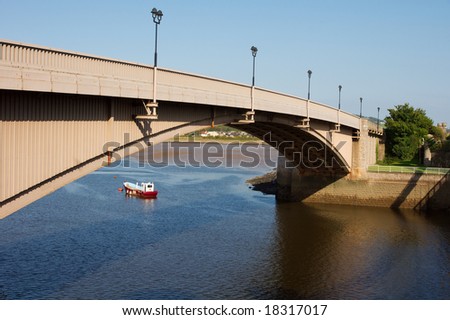 A bridge over the water with a boat underneath. The sky is brilliant blue on an end-of-summer day.