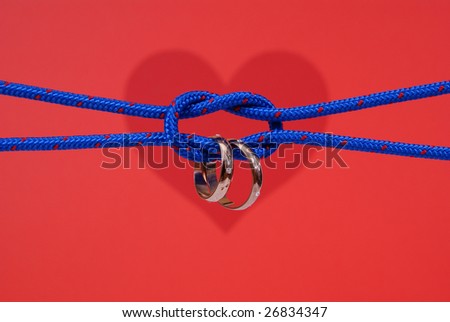 connected strings with golden wedding rings on red background