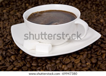 cup with coffee on spilled grains of coffee